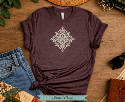 Heather Maroon t-shirt with a cream mandala design on a wooden surface.