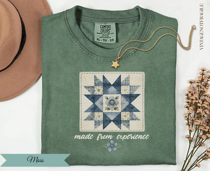 Green t-shirt with a blue quilted flower design and "made from experience" text.