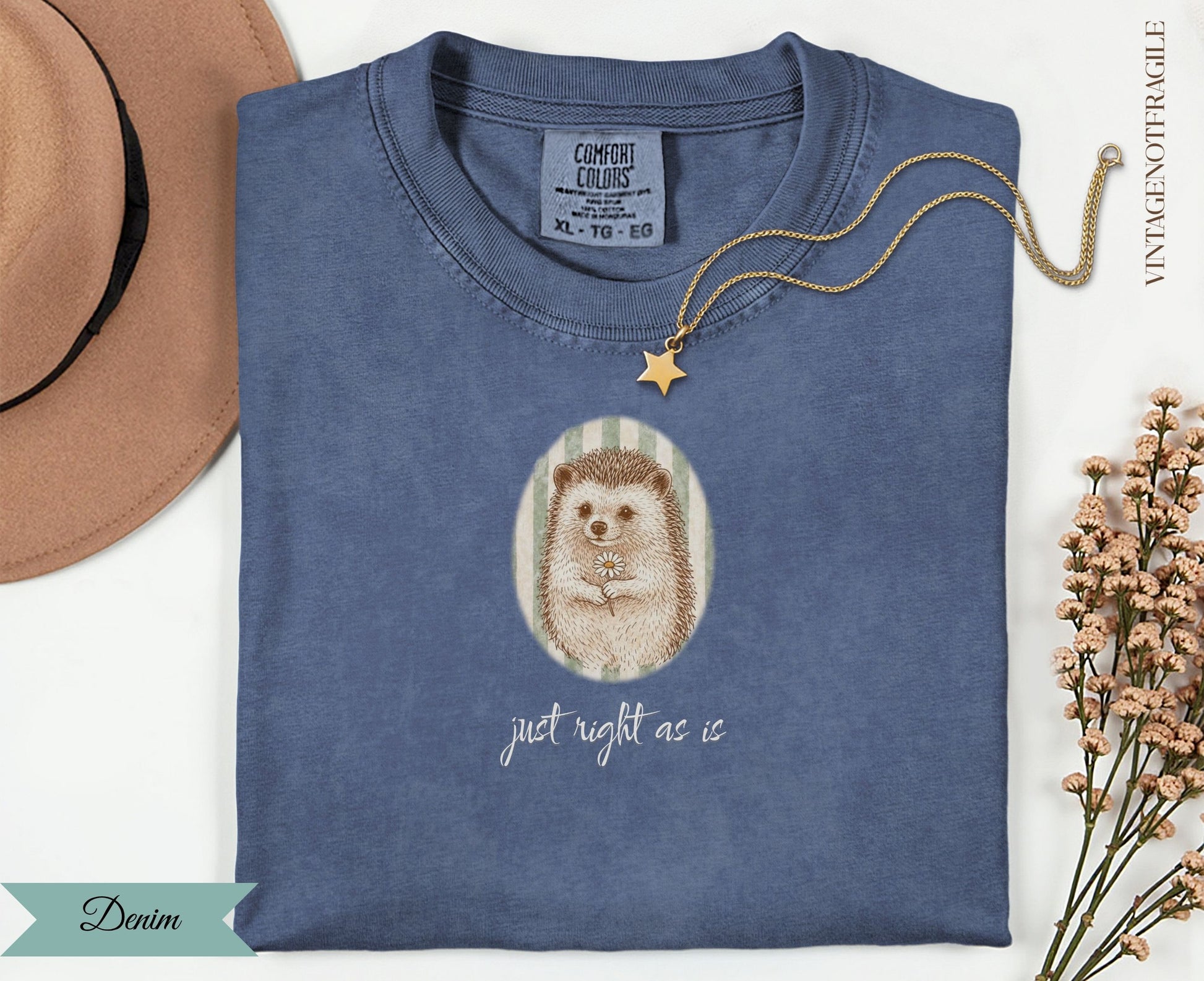 Blue t-shirt with a hedgehog and daisy illustration, text "just right as is".