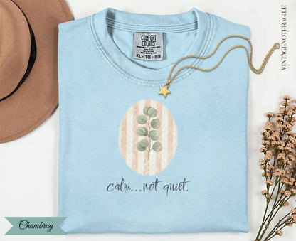 Light blue t-shirt with oval eucalyptus design and "calm...not quiet." text.