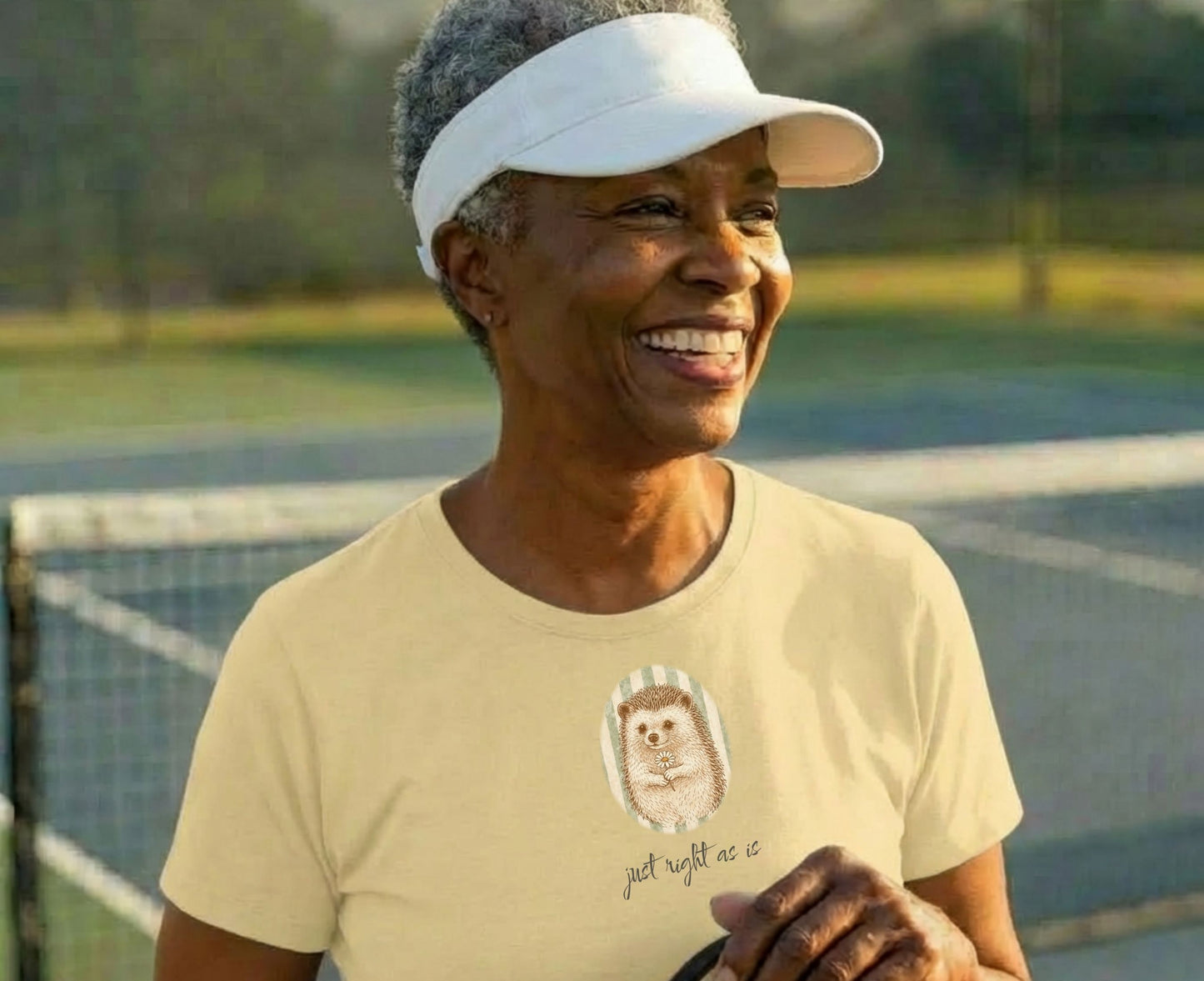 Woman wearing a light yellow t-shirt with a hedgehog graphic and text.