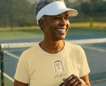 Woman wearing a light yellow t-shirt with a hedgehog graphic and text.