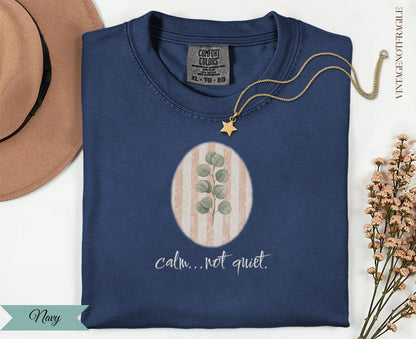 Navy t-shirt with oval floral design and "calm... not quiet" text.