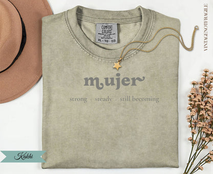 Khaki t-shirt with "mujer strong steady still becoming" text and gold necklace.
