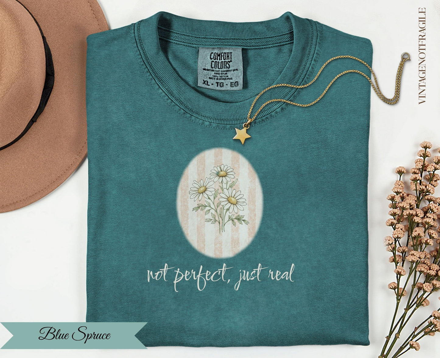 Teal t-shirt with "not perfect, just real" and daisy graphic.