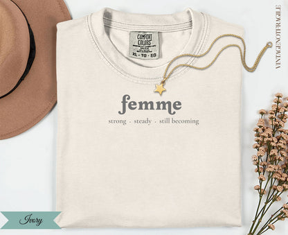 Cream t-shirt with "femme strong. steady. still becoming" text.