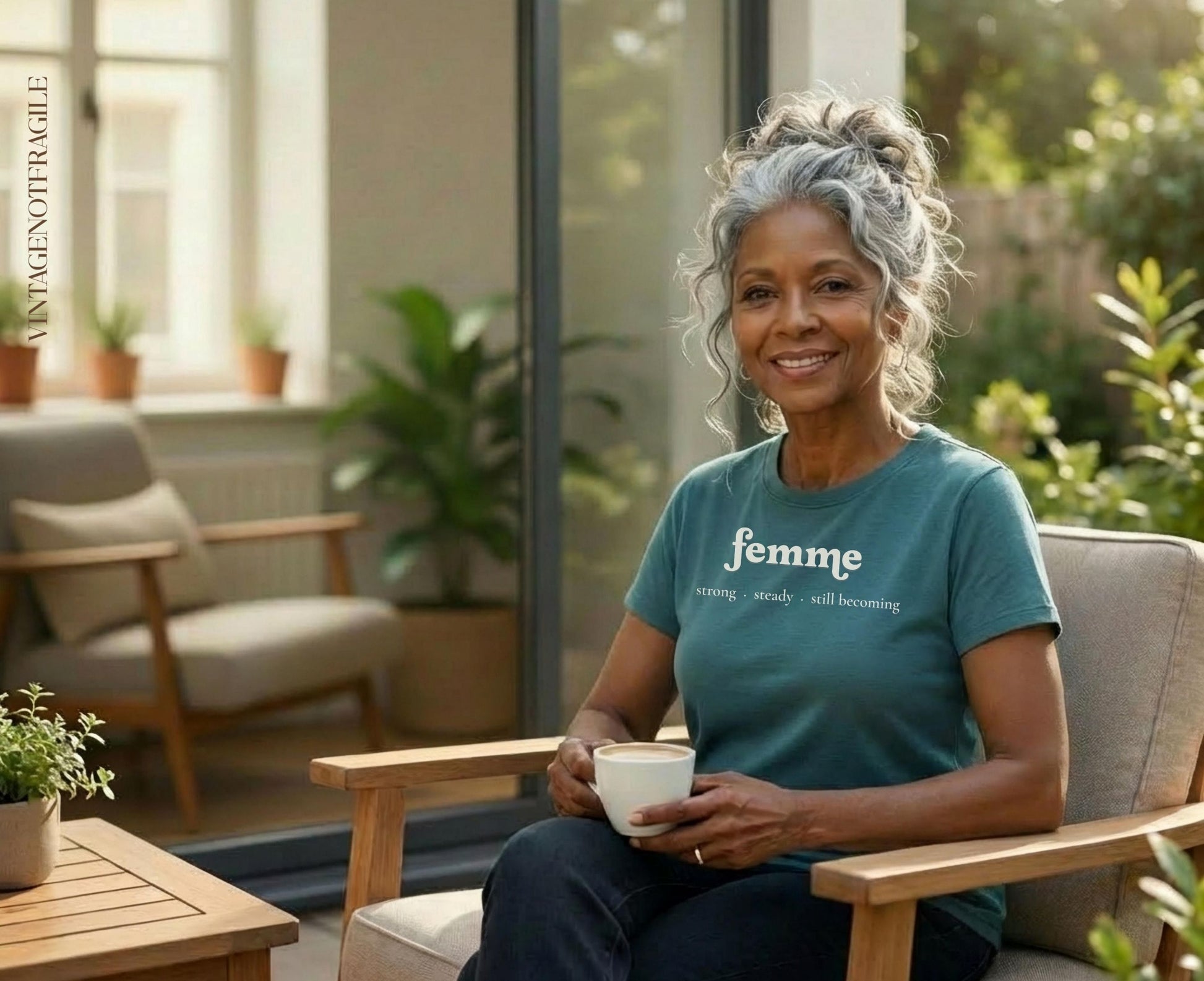 Woman with gray hair in bun wearing "femme" t-shirt, holding a coffee mug.