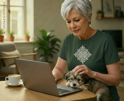 Woman petting a puppy while looking at a laptop with a cup of coffee.