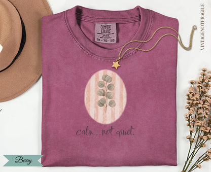 Berry colored t-shirt with "calm...not quiet" and botanical graphic.