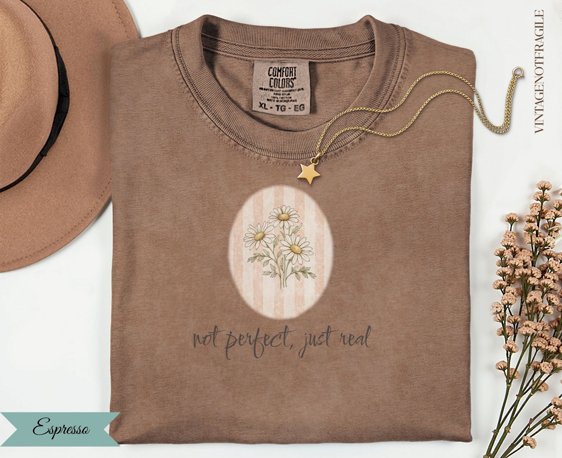 Espresso colored t-shirt with daisy graphic and "not perfect, just real" text.