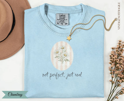 Light blue Comfort Colors t-shirt with "not perfect, just real" text and daisy graphic.