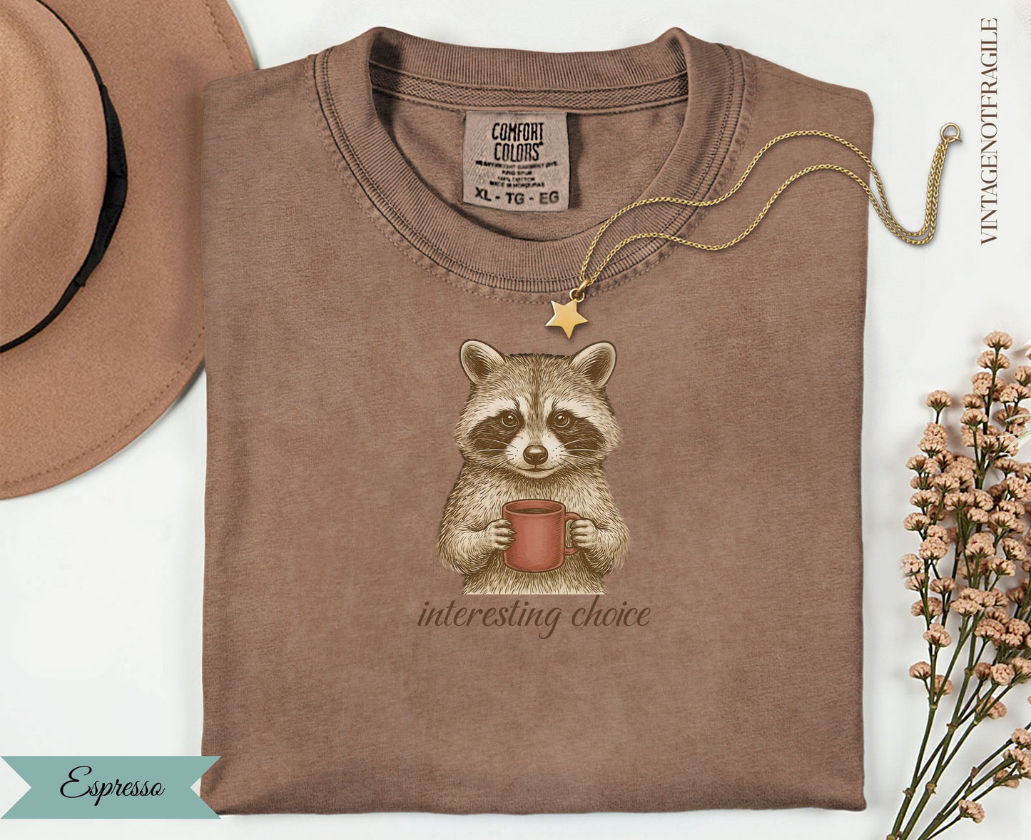 Brown t-shirt with raccoon holding coffee cup and "interesting choice" text.