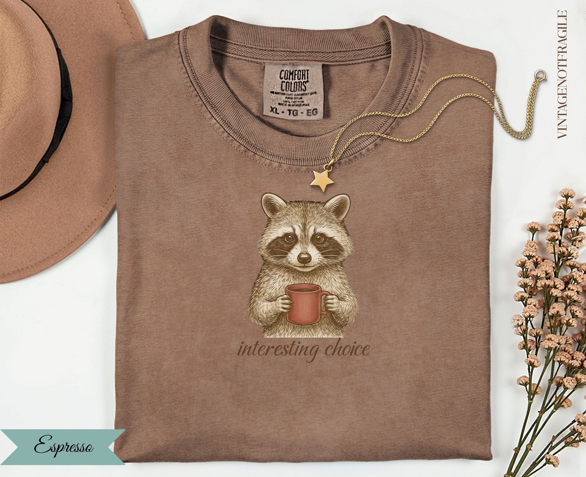 Brown t-shirt with raccoon holding coffee cup and "interesting choice" text.