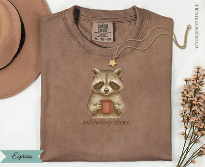 Brown t-shirt with raccoon holding coffee cup and "interesting choice" text.