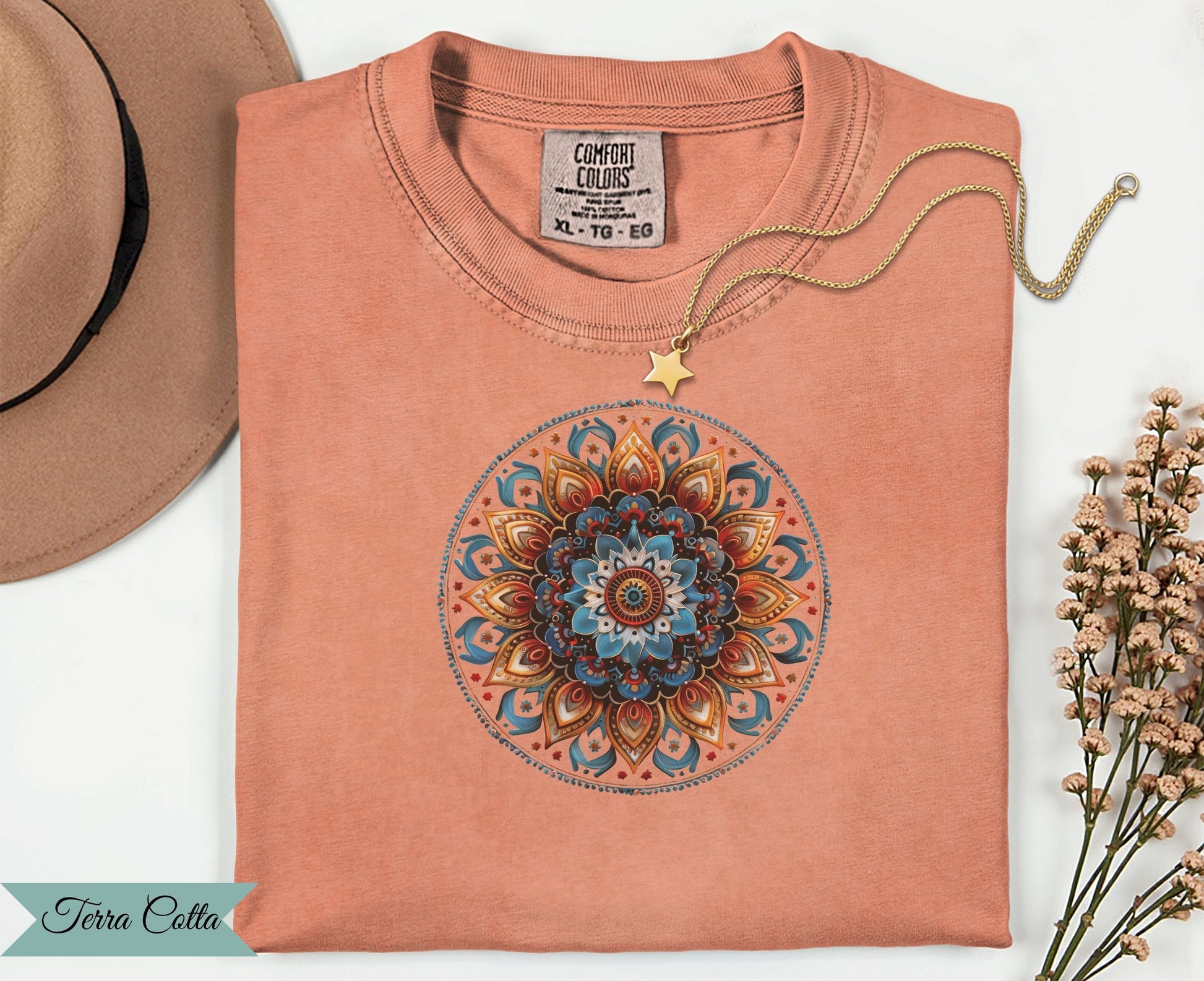 Coral t-shirt with mandala design and gold star necklace.