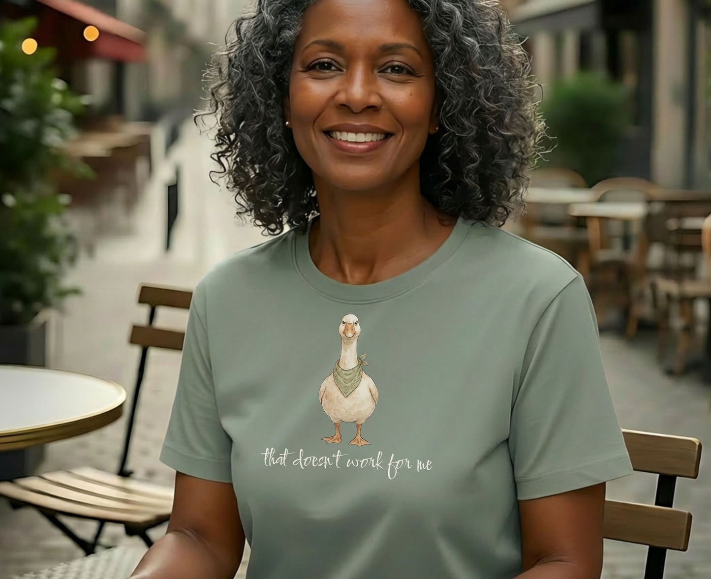 Woman wearing a sage green t-shirt with a duck wearing a bandana, saying "that doesn't work for me."