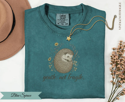 Teal t-shirt with hedgehog illustration and "gentle. not fragile." text.