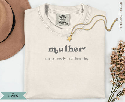 Cream t-shirt with "mulher strong steady. still becoming" text and gold necklace.