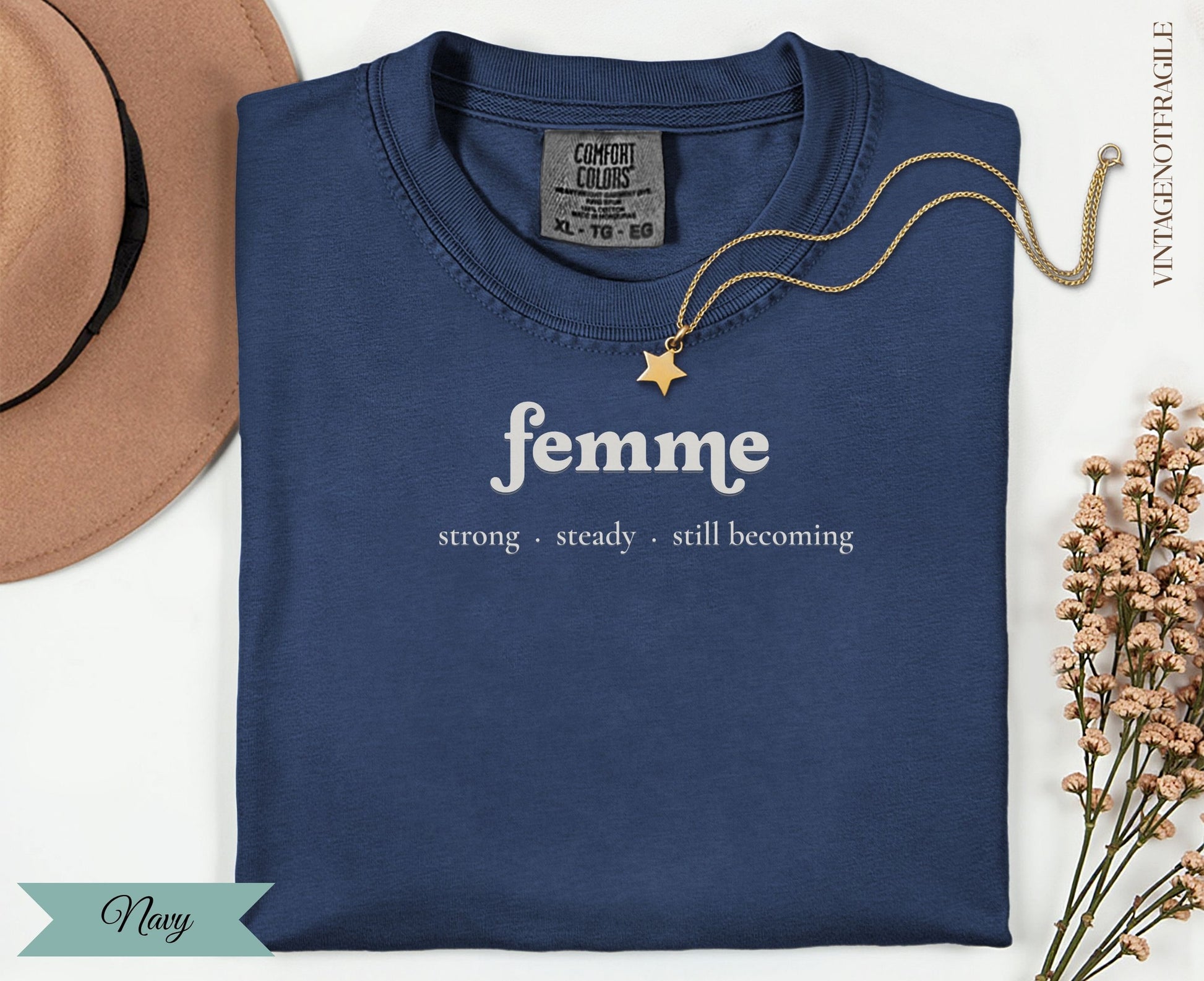 Navy t-shirt with "femme strong steady. still becoming" text, gold necklace.