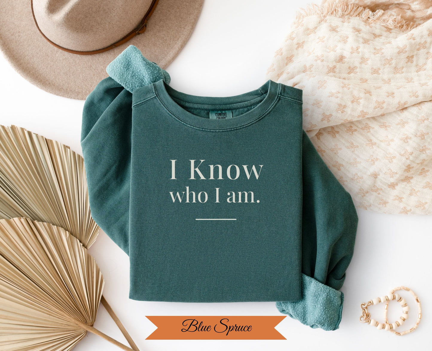 Teal sweatshirt with "I Know who I am." text and decorative elements.