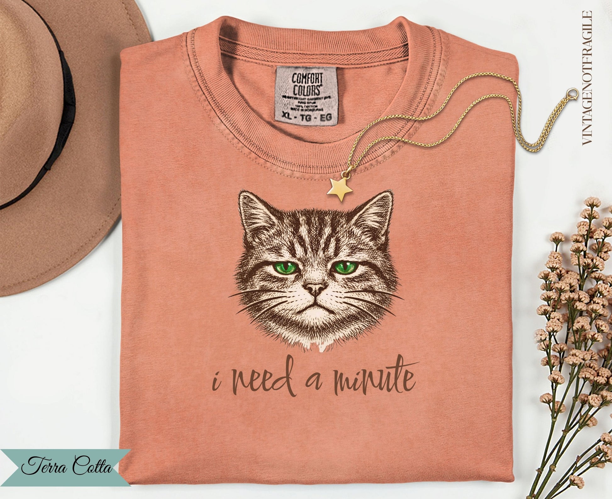 Graphic tee with a cat face and "i need a minute" text.