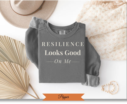 Comfort Colors graphic sweatshirt with "Resilience Looks Good On Me" text.