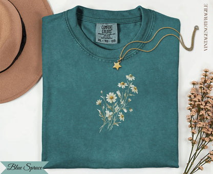 Teal t-shirt with embroidered white daisies and "Blue Spruce" text.