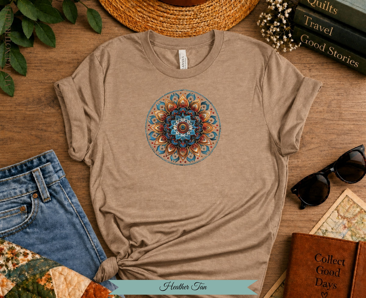 Heather tan t-shirt with a colorful mandala design, denim jeans, and sunglasses.