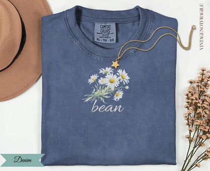 Denim t-shirt with white daisy bouquet graphic and "bean" text.