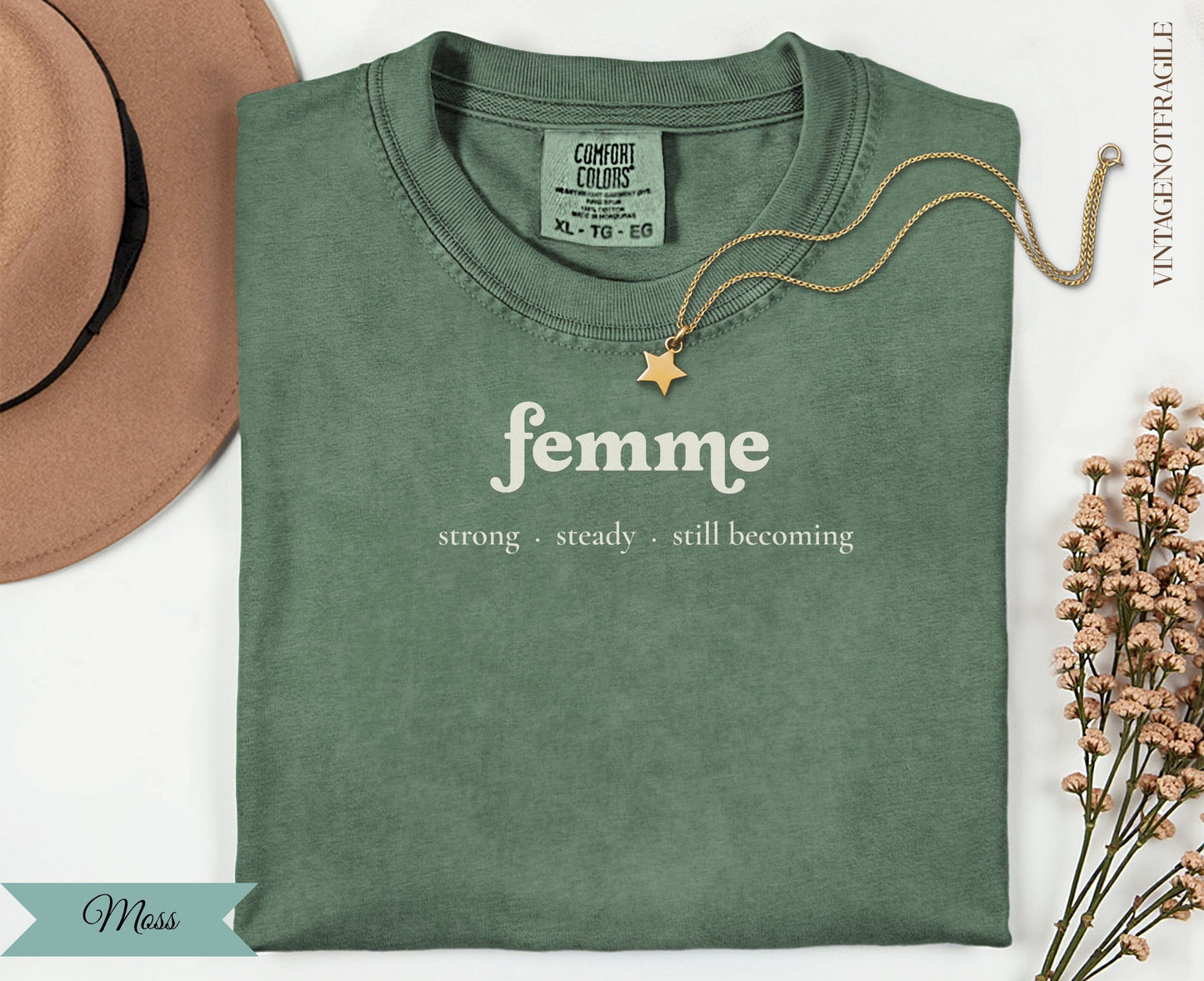 Sage green t-shirt with "femme strong steady. still becoming" text.