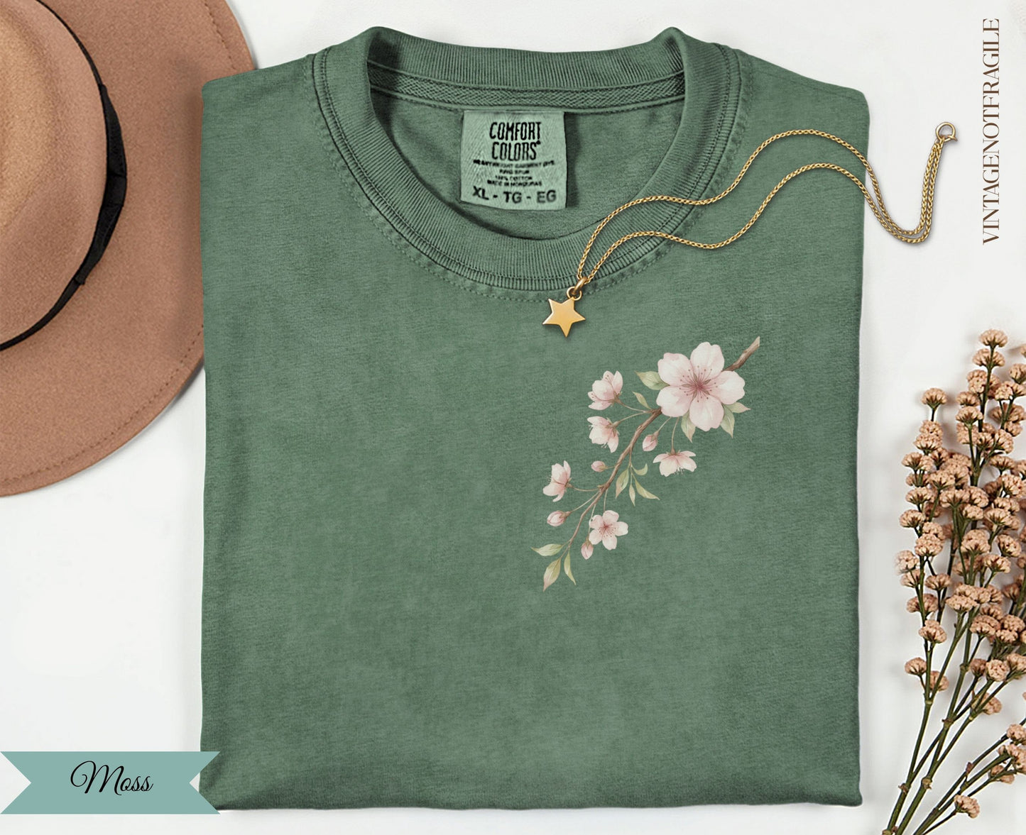 Green t-shirt with a pink cherry blossom branch graphic and "Comfort Colors" label.