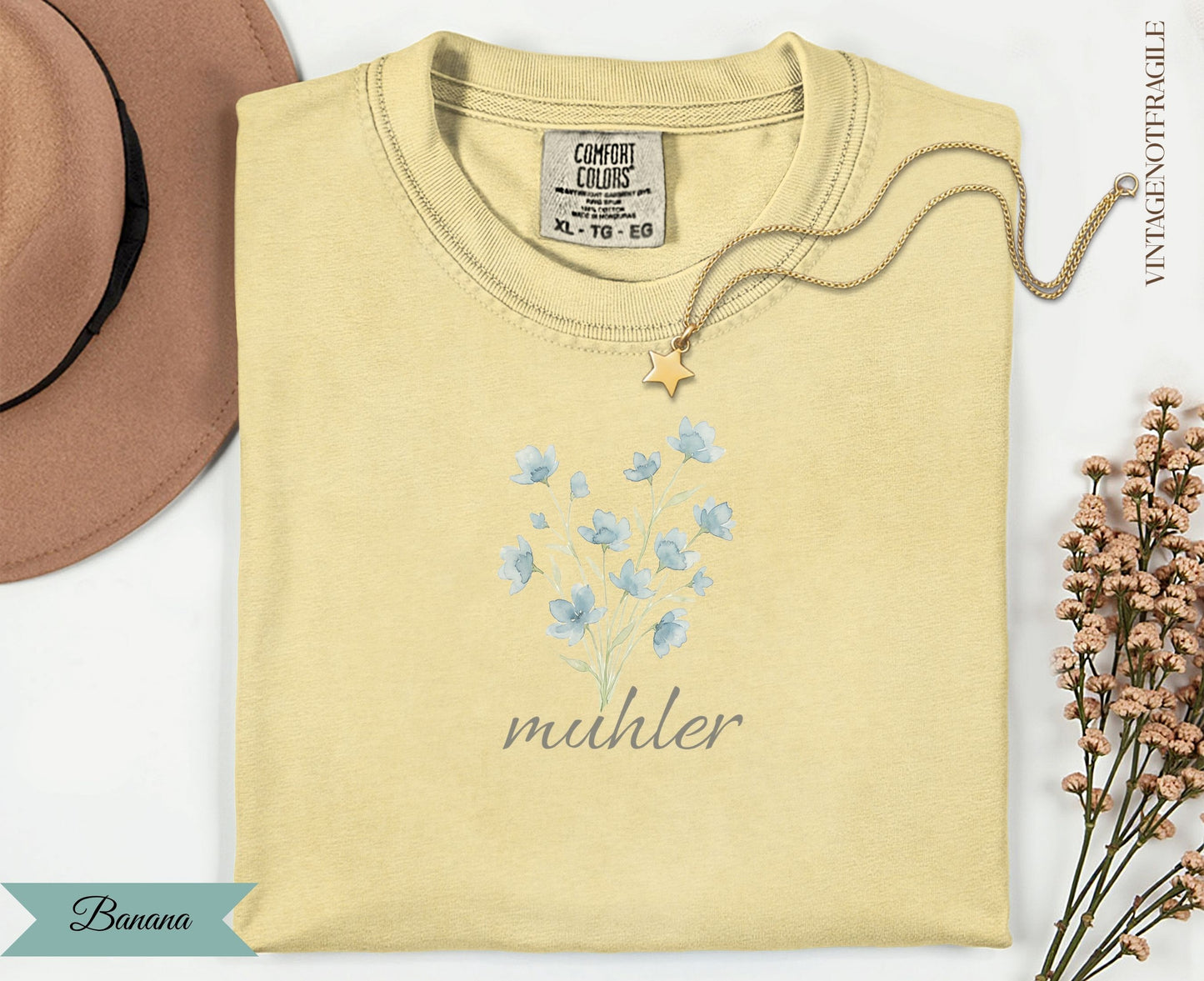 Light yellow t-shirt with blue floral design and "muhler" text.