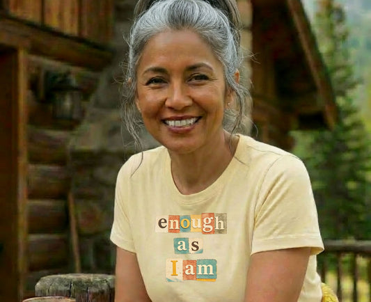 Woman wearing a light yellow t-shirt with "enough as I am" text.