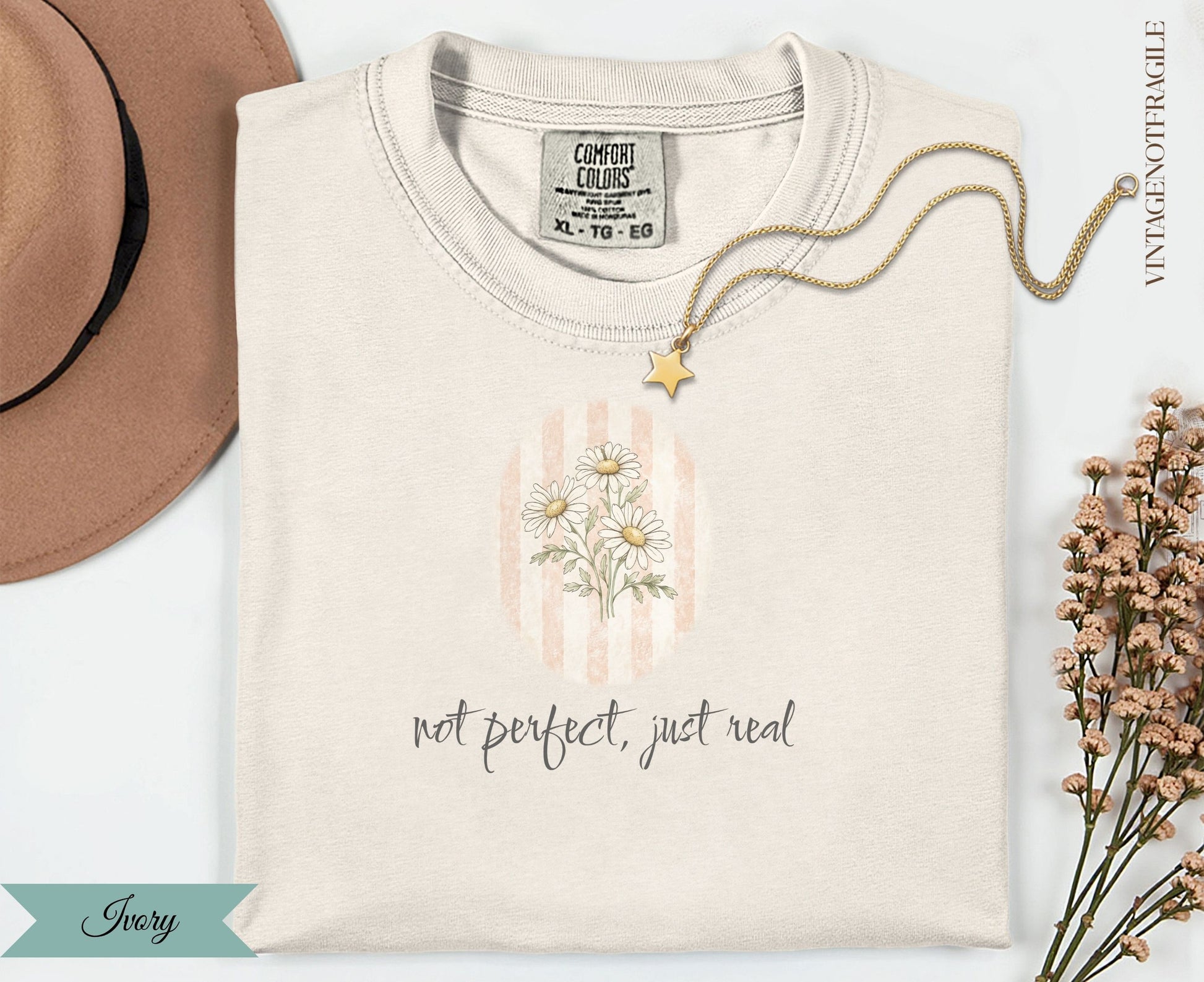 Ivory t-shirt with daisy floral graphic and "not perfect, just real" text.