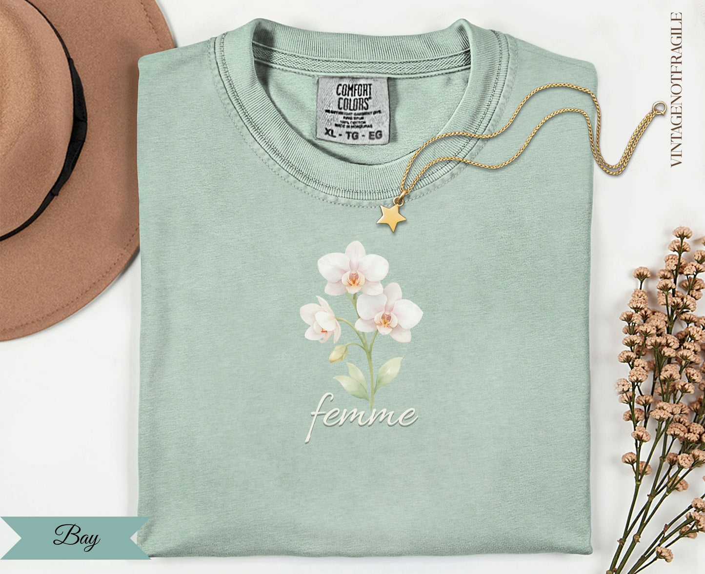 Light mint t-shirt with "femme" and orchid graphic, gold necklace.