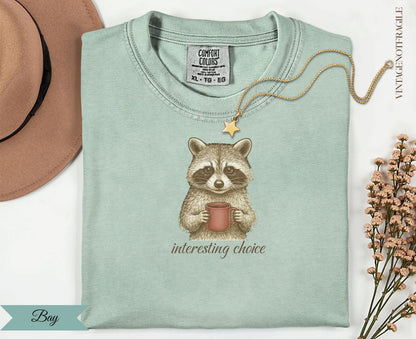 Raccoon in mint green t-shirt holding a red mug, "interesting choice" text.