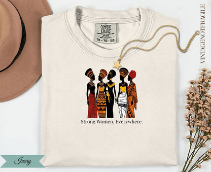 Ivory t-shirt with diverse women in traditional attire, text "Strong Women. Everywhere."
