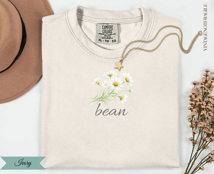 Cream t-shirt with a watercolor daisy bouquet and "bean" text.
