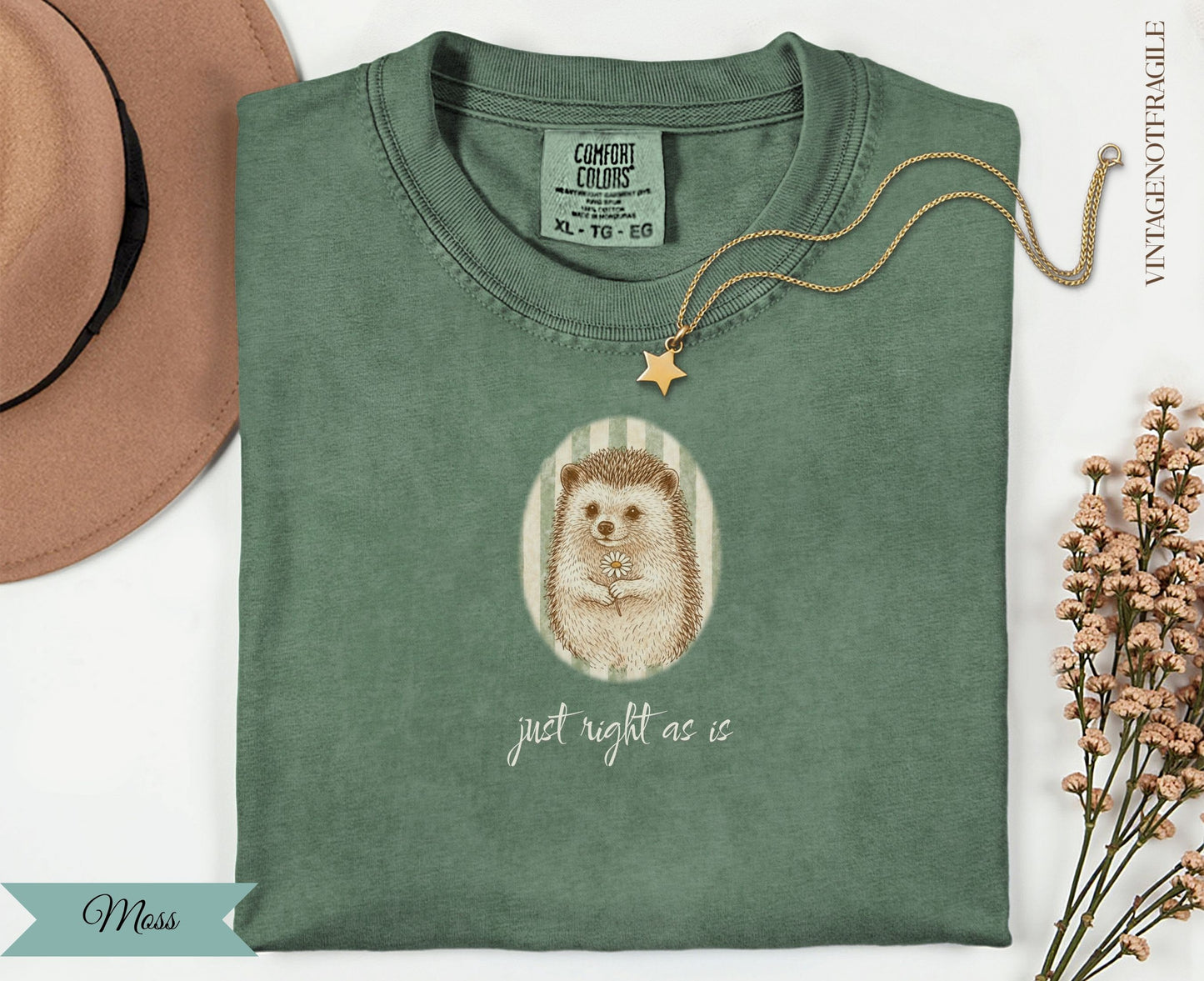 Green t-shirt with hedgehog holding a daisy, "just right as is" text.