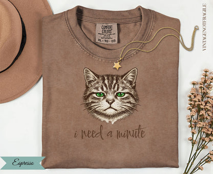 Brown t-shirt with a cat's face and "i need a minute" text.