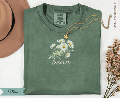 Green t-shirt with white daisies and "bean" text.
