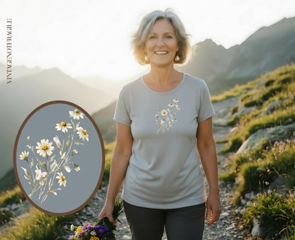 Woman in gray t-shirt holding flowers with daisies on shirt.