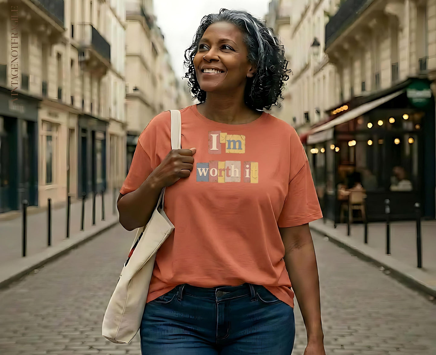 Woman wearing an orange t-shirt with "I'm worth it" text, walking on a street.