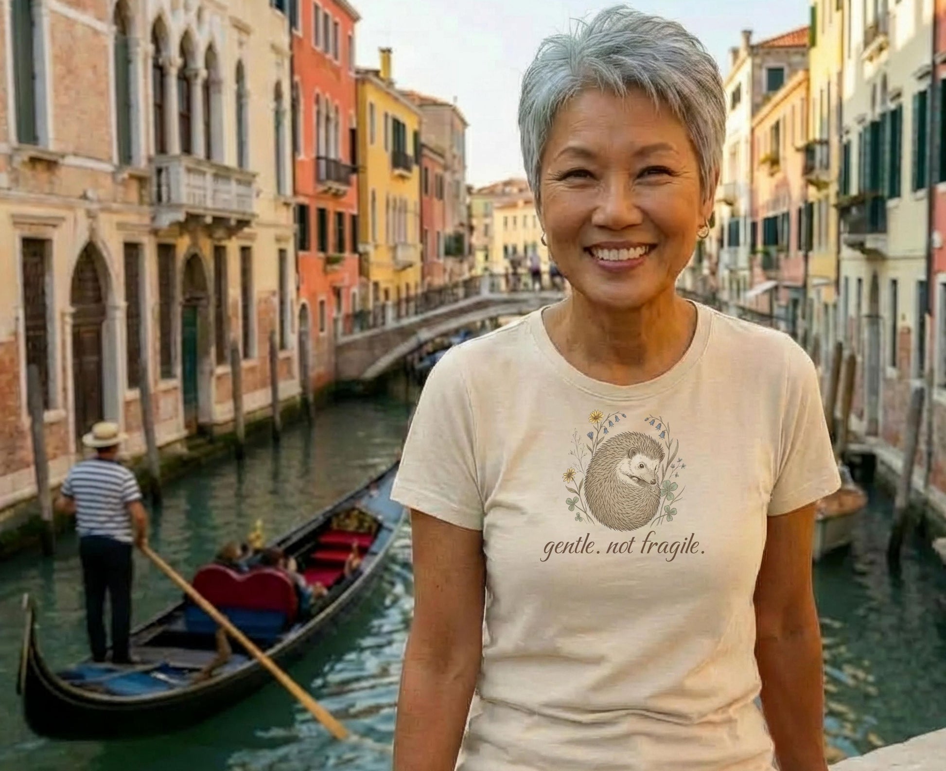 Woman smiles, wearing a light-colored t-shirt with a hedgehog graphic and text.