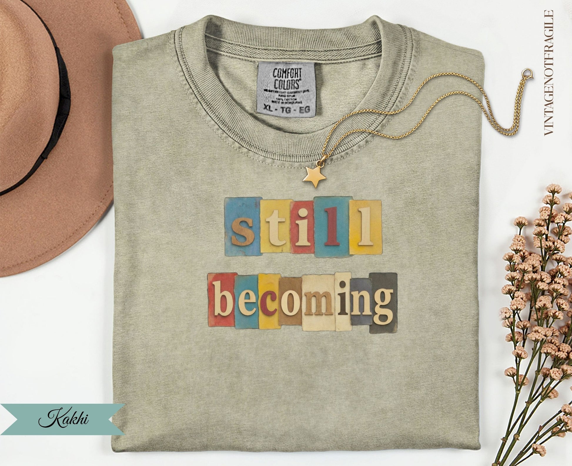 T-shirt with "still becoming" in colorful block letters.
