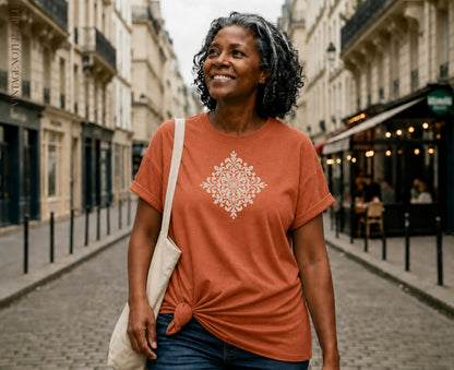 Woman wearing orange t-shirt with white mandala design, carrying tote bag.