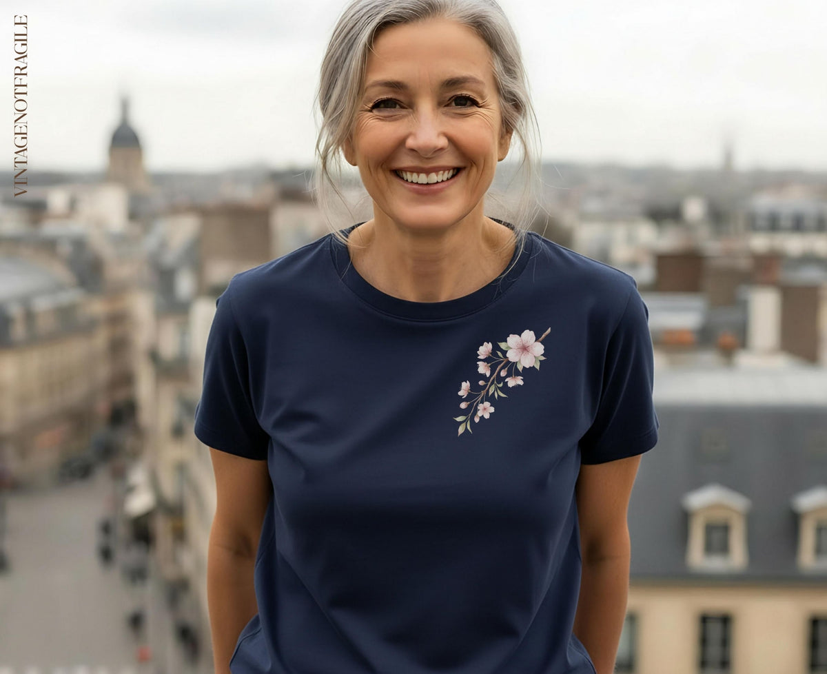 Woman smiling in a navy blue t-shirt with a light pink floral design.