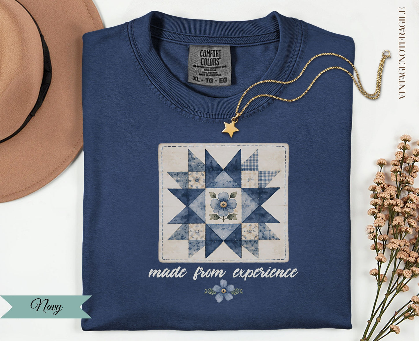 Navy t-shirt with a blue floral quilt square design and "made from experience" text.