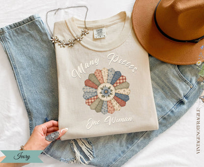 Cream sweatshirt with "Many Pieces. One Woman." text and a floral quilt design.