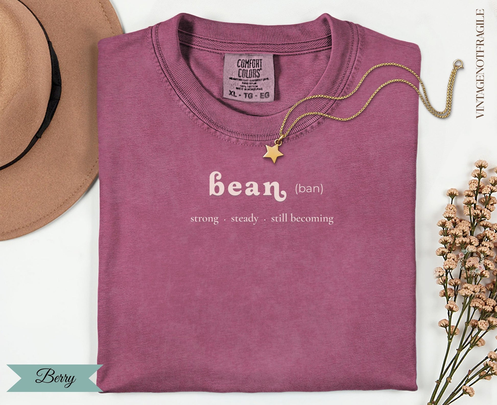 Berry colored t-shirt with "bean" text and gold star necklace.